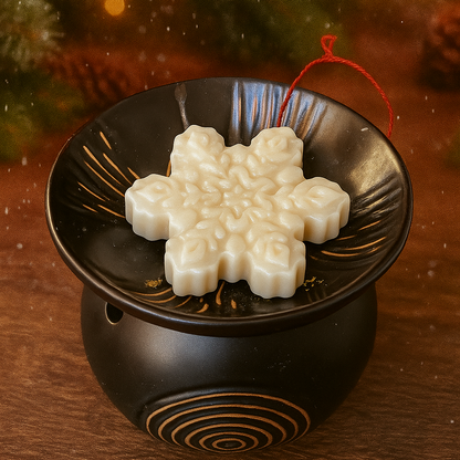 Decorative snowflake ornamelt in a wax melter with a Christmas tree in the background