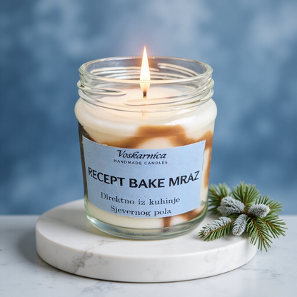 Candle in a glass jar with a label on a marble coaster, surrounded by a sprig of pine.