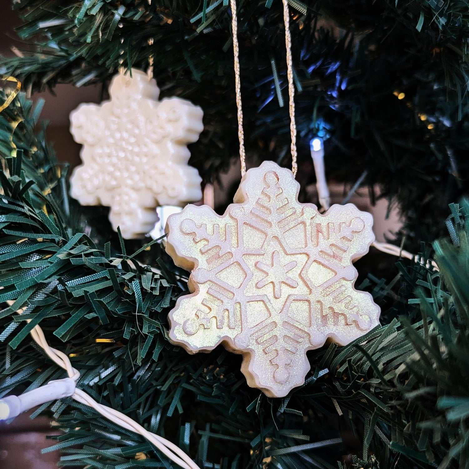 Snowflake-shaped ornamelts hanging on a Christmas tree