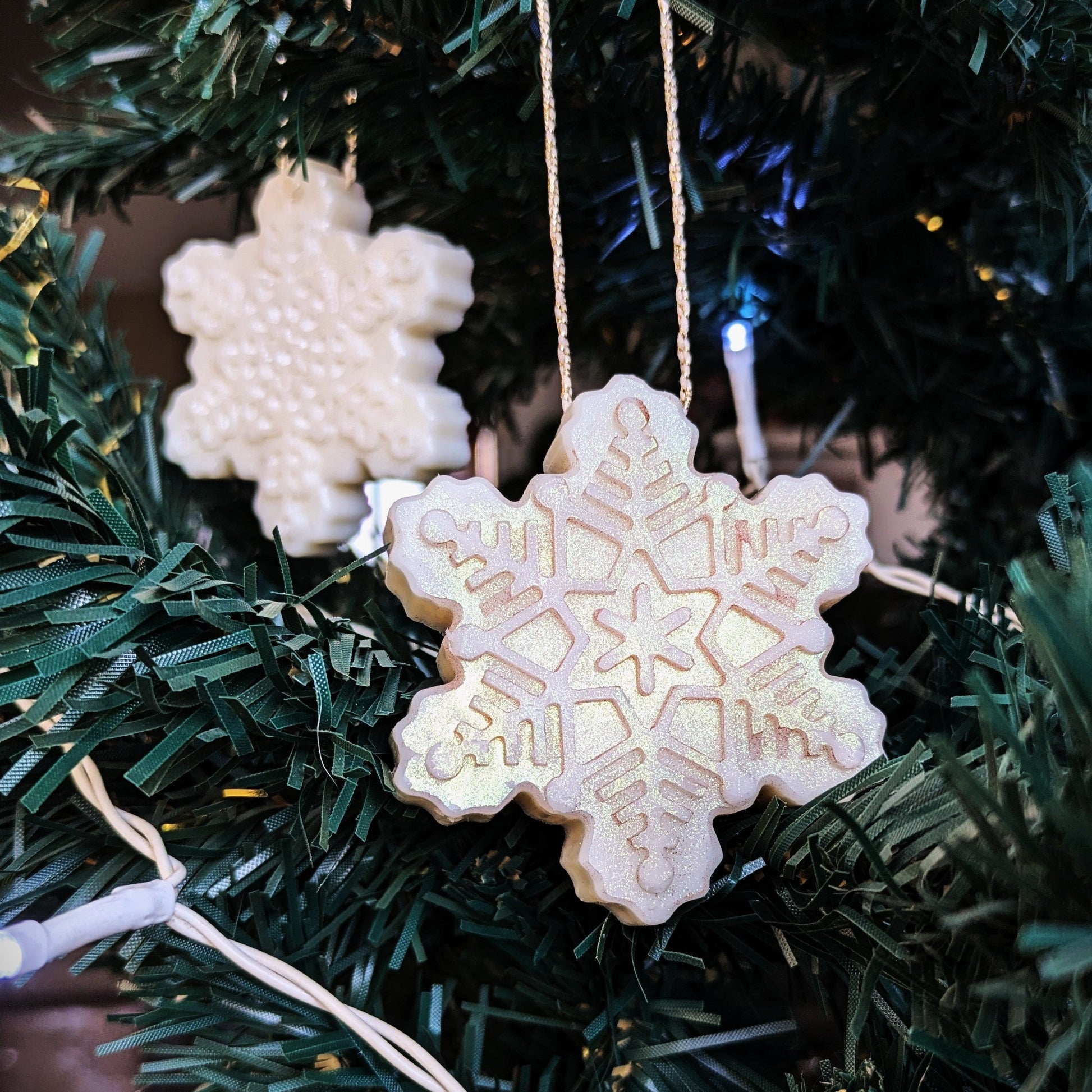Snowflake-shaped ornamelts hanging on a Christmas tree